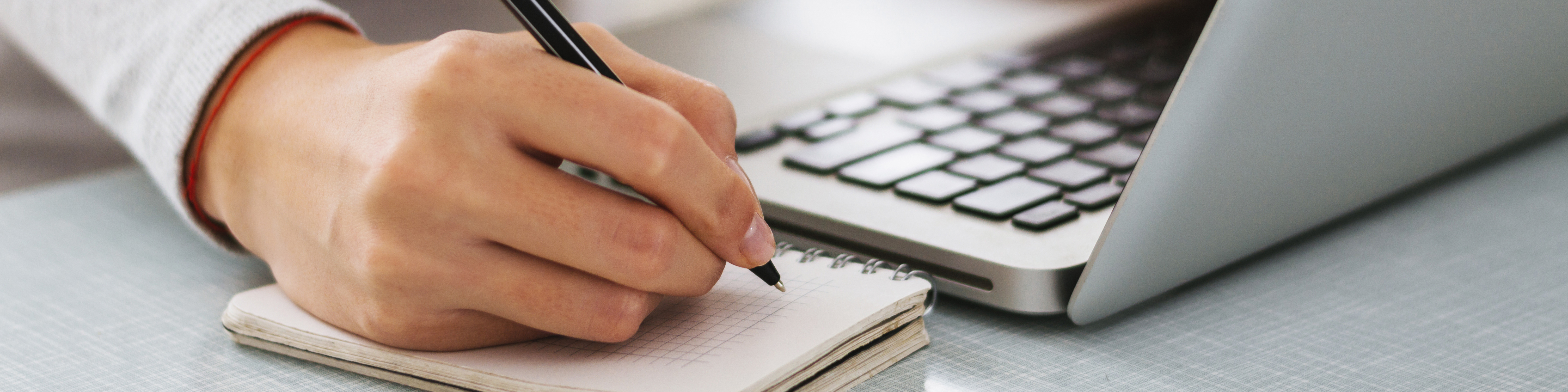 woman writing next to laptop