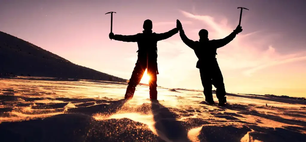 silhouette of two people mountain climbing