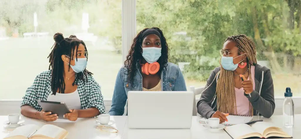 three women with masks at laptops