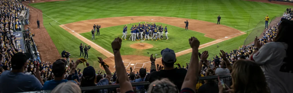Milwaukee Brewers players celebrating their World Series championship on the field as fans cheer from the stands.